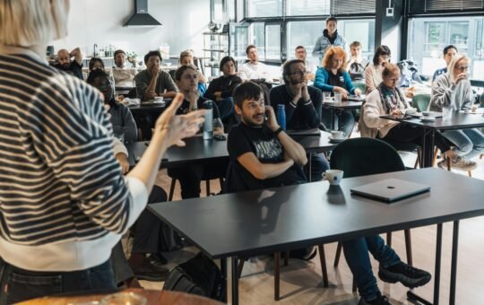 A presenter engages an attentive audience during a business workshop indoors.